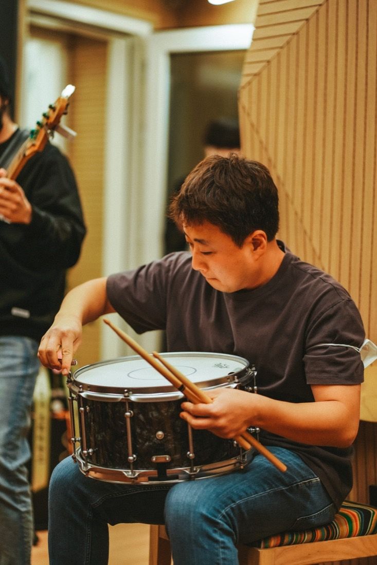 A drummer checking a snare during a session